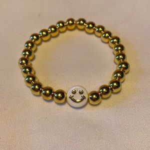 Gold beaded bracelet with a white and gold smiley face